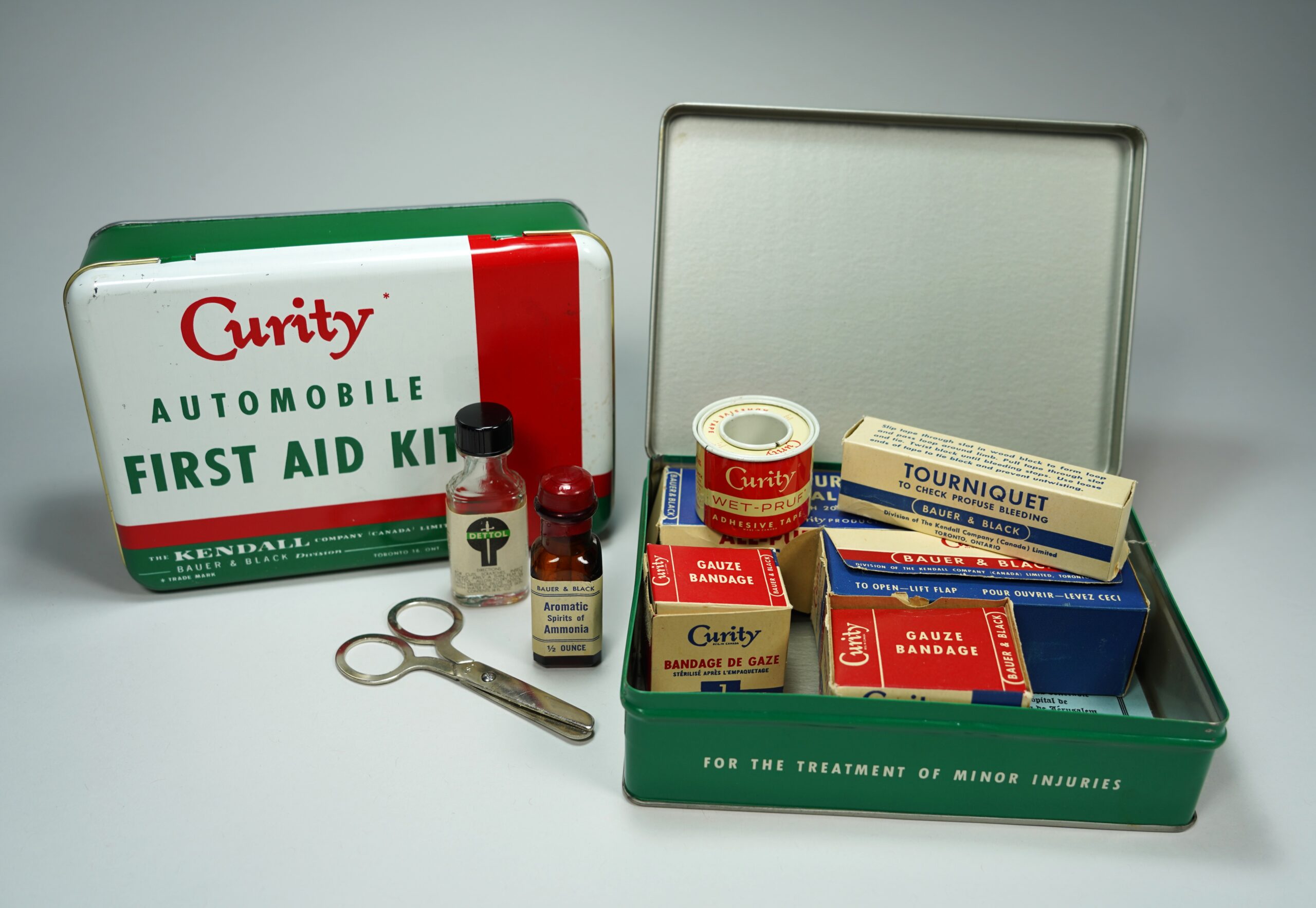 Vintage First Aid Kit on a table with its materials inside and surrounding it.