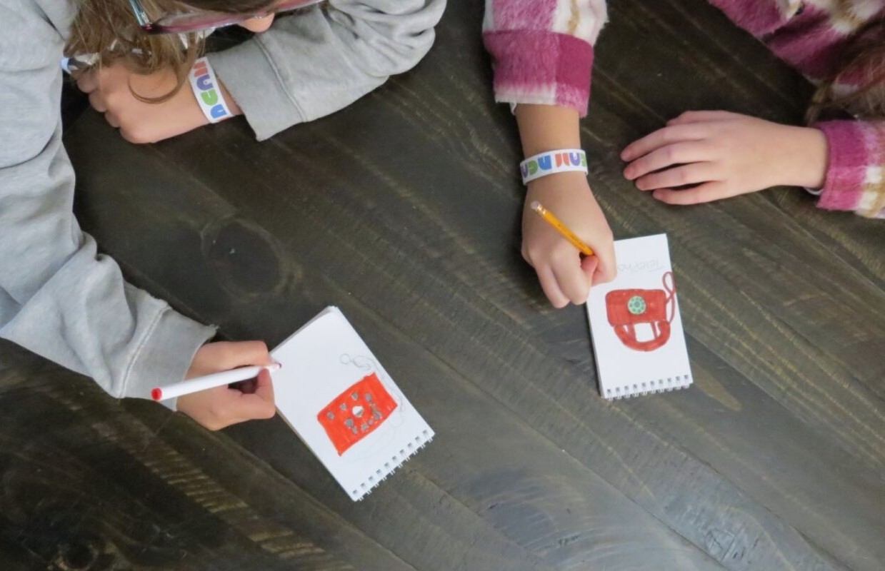 Two young children drawing in notebooks.
